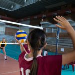 Female players playing volleyball in the court