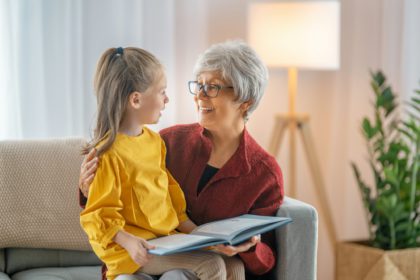 Grandmother reading a book to granddaughter.