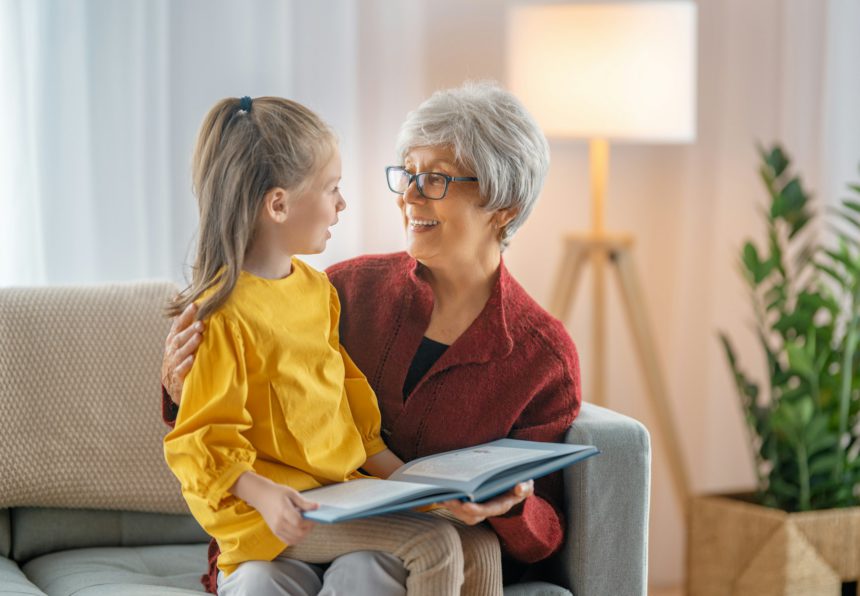 Grandmother reading a book to granddaughter.