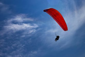 One paraglider is flying in the blue sky.